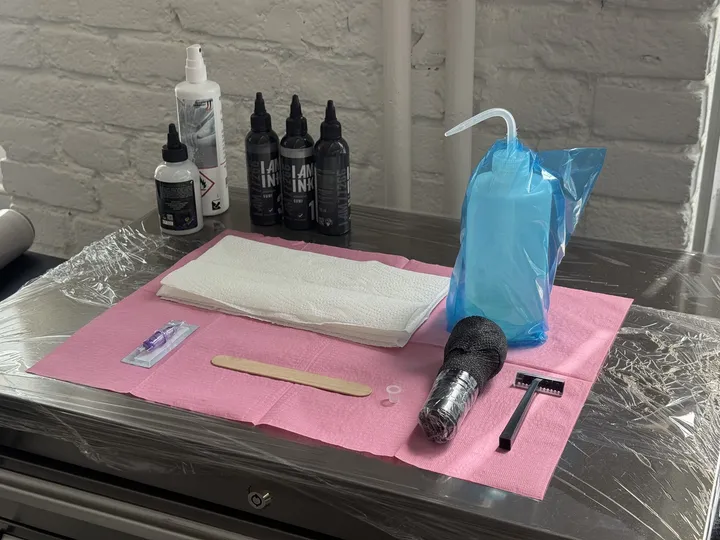 A fresh station: sealed inks, single-use razor and barrier film laid out before a session